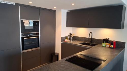 une cuisine avec des armoires noires et un comptoir dans l'établissement Cannes Centre - Villa Lérins - Cavell Suites - Walking Distance From Palais des Festivals and Beach - Free Parking - Perfect Location For Business And Holliday, à Cannes