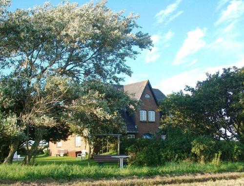 a large brick house with a bench in front of it at Haus Wolfram App Gondeline Morsumer Kliff in Archsum