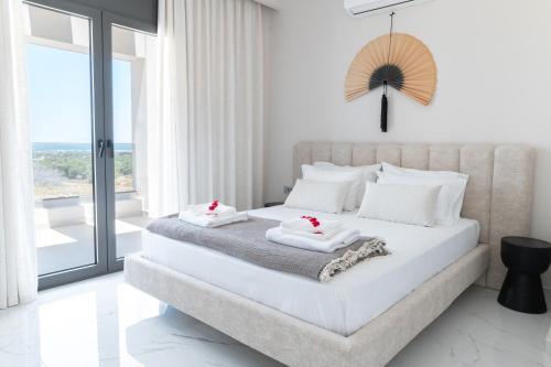 ein weißes Schlafzimmer mit einem großen Bett mit Handtüchern darauf in der Unterkunft Villa Jaubelli Bliss in Platánion