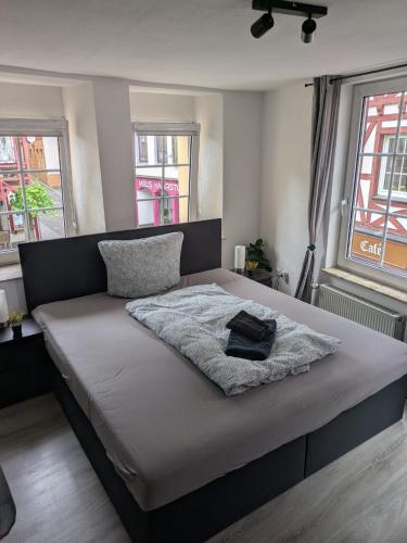 a bedroom with a bed with a blanket and two windows at FeWo Innenstadt mit Parkplatz in 200m Entfernung bis 4 Personen, 80m bis Markplatz in Cochem