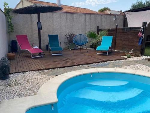- une terrasse avec des chaises et un parasol à côté de la piscine dans l'établissement Cocon à quelques minutes des plages du Roussillon, à Saint-Nazaire