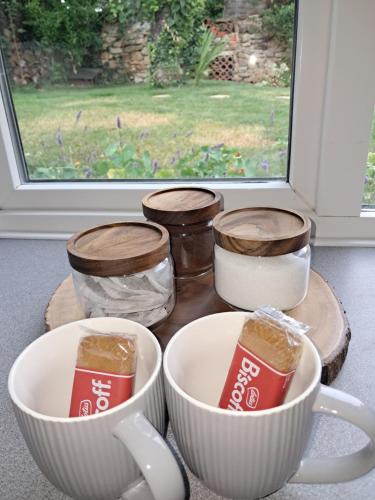 a group of bowls and cups on a table with a window at Robin's nest in Wilbarston