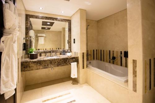 a bathroom with a tub and a large mirror at Jannah Burj Al Sarab in Abu Dhabi