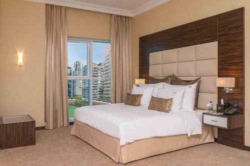 a bedroom with a large bed and a large window at Jannah Burj Al Sarab in Abu Dhabi