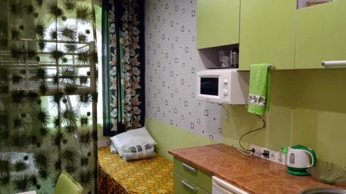 una piccola cucina con mobili verdi e un forno a microonde di Vitalija a Riga