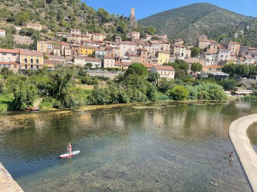 a person on a surfboard in a river in a town at La Retraite in Assignan