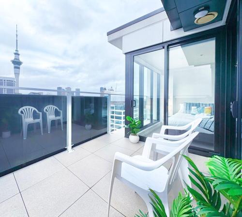 a balcony with white chairs and a view of the city at Sky Tower Views High-Floor Apt Pool Gym Access in Auckland
