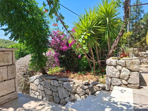 a garden with pink flowers and a stone wall at Holiday house Bore in Babino Polje