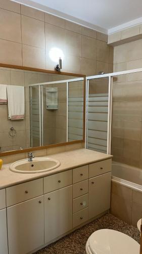 a bathroom with a sink and a mirror and a toilet at Apartamento de Férias in São Félix da Marinha