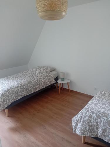 a bedroom with two beds and a small table at Le gîte du Bonheur tranquille in Épégard
