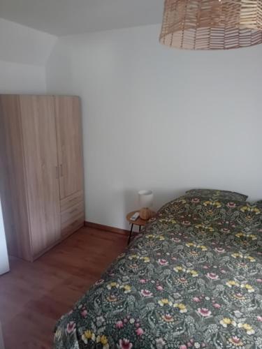 a bedroom with a bed with a floral bedspread at Le gîte du Bonheur tranquille in Épégard