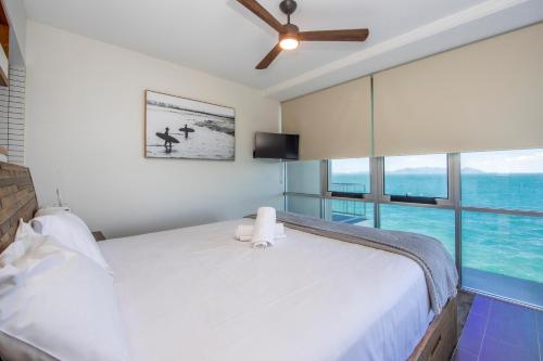 a bedroom with a white bed and a large window at Luxury Oceanview Escape in Nelly Bay