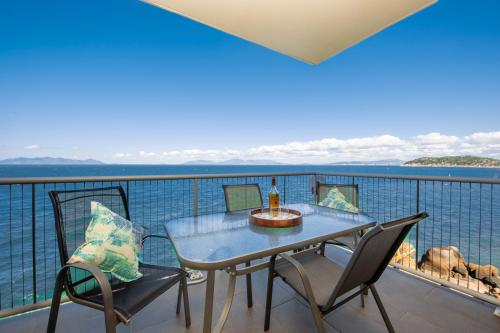 a table and chairs on a balcony overlooking the water at Luxury Oceanview Escape in Nelly Bay