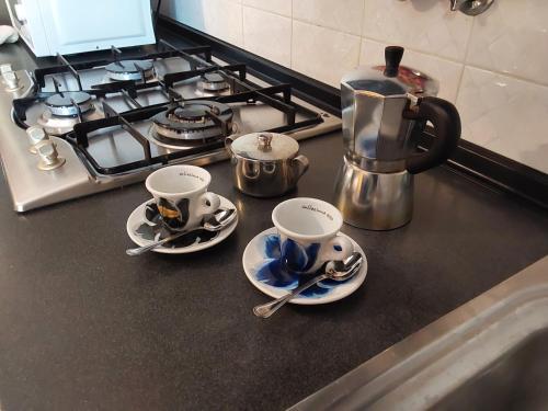 two cups and saucers on a counter next to a stove at casa roberta e gilberto in Bologna