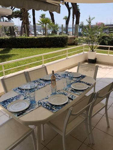 a white table with plates and wine glasses on it at T2 & Garage FRONT DE MER résidence de Standing in Fréjus