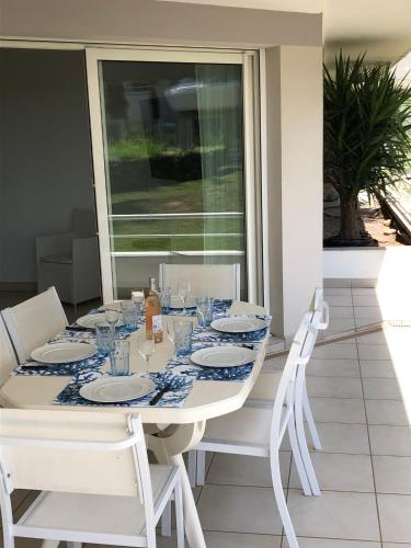 une table à manger blanche avec des chaises blanches et une nappe bleue et blanche dans l'établissement FRONT DE MER, Résidence de Standing avec garage, à Fréjus