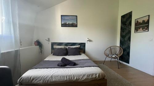 Un dormitorio con una cama y una silla dentro. en Studio Sydney Charme et jardin I séjour pro ou romantique, en Châtellerault