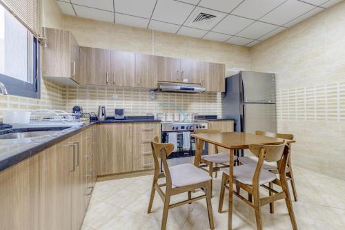 a kitchen with a table and chairs and a refrigerator at Beautiful Villa with Sea Views and Jacuzzi, Near Diving, Paddle Boating and Camping Spots, Sharm Al Dana Villa, Fujairah by Deluxe Holiday Homes in Fujairah
