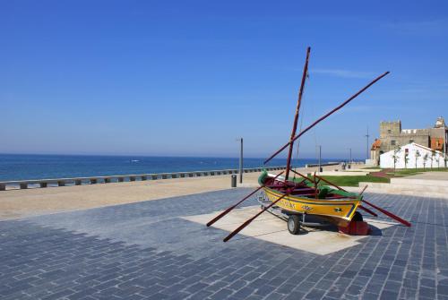 a small boat sitting on a sidewalk next to the ocean at Apulia Praia Hotel in Esposende