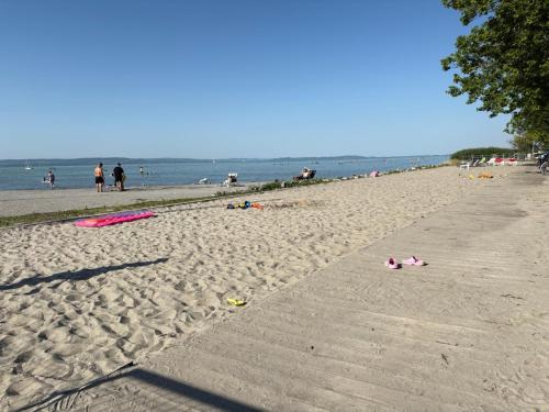 a sandy beach with people and the ocean in the background at BL Residence Balatonlelle in Balatonlelle