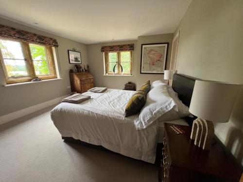 a bedroom with a bed and a table and two windows at Everdon Hill House - B&B in Great Everdon