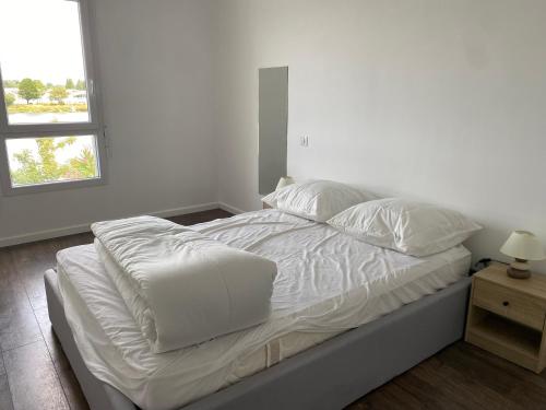 - un lit avec des draps blancs et un ordinateur portable dans l'établissement Bayonne-15 mn du centre - vue magnifique, à Bayonne