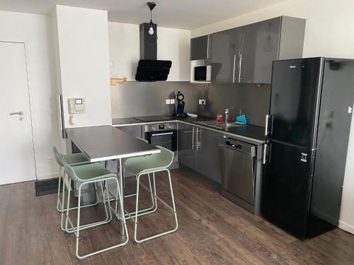 Il comprend une cuisine équipée d'un réfrigérateur noir, d'une table et de chaises. dans l'établissement Bayonne-15 mn du centre - vue magnifique, à Bayonne