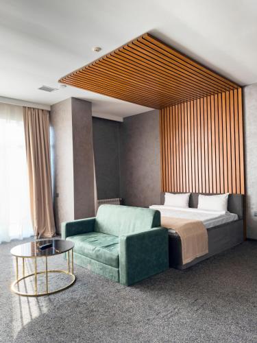 a bedroom with a bed and a green couch at Mona Hotel and Cottages in Lankaran