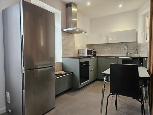 une cuisine avec un réfrigérateur en acier inoxydable et une table dans l'établissement Charme & Clim Place Chateauneuf - Coeur de Tours, à Tours