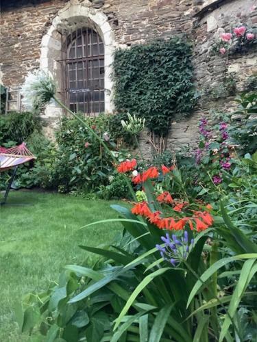 a garden with flowers in front of a brick building at LES AUGUSTINS, chambres d'hôtes, quartier historique, accueil 2 roues in Angers