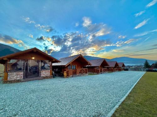 a row of wooden cabins on a gravel road at Stâna Boierilor in Gura Rîului