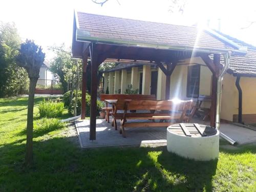 a wooden pavilion with a bench in a yard at Aranyhal Vendégház in Poroszló
