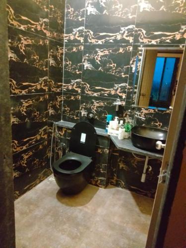 a bathroom with a black toilet and a sink at Maharaja foothills Courtyard 4 BHK Villa with Pool in Kolvan