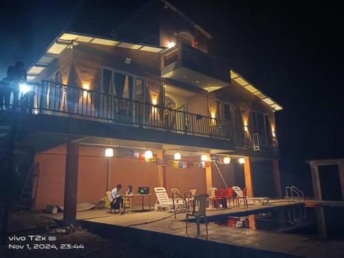 a person sitting at a table on the balcony of a building at Maharaja foothills Courtyard 4 BHK Villa with Pool in Kolvan