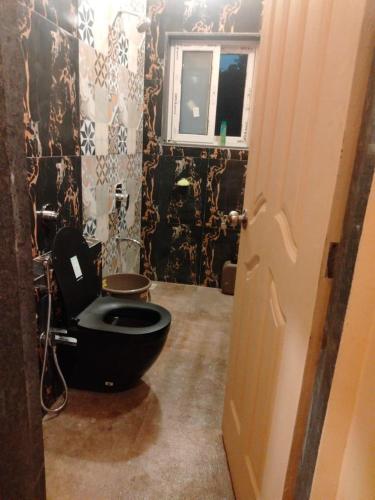 a bathroom with a black toilet and a window at Maharaja foothills Courtyard 4 BHK Villa with Pool in Kolvan