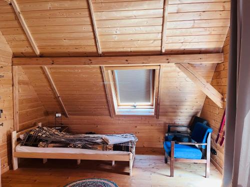 a room with a bed and a chair in a cabin at Wioska Mnicha - Dom na końcu in Knyszyn
