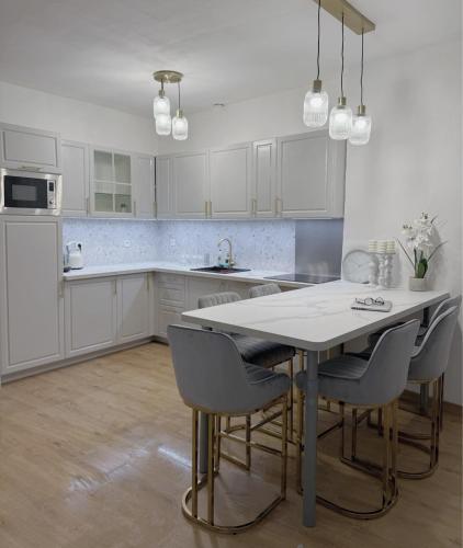 une cuisine avec des armoires blanches et une table et des chaises dans l'établissement Art&Heart - Centre historique, idéal Feria de Béziers, à Béziers