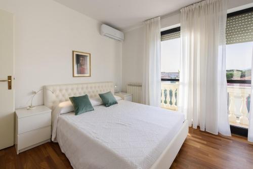 a white bedroom with a large white bed with green pillows at GOLDEN LUXE - Royal Sea View Private Parking in Marina di Pietrasanta