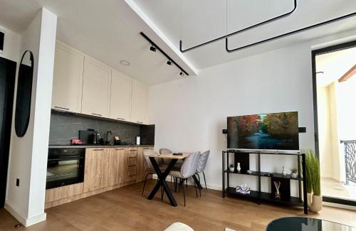 Una cocina con gabinetes blancos y una mesa con sillas. en Terra29 apartman, zlatiborski kutak sa besplatnim parkingom, en Zlatibor