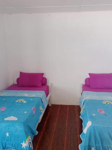 two beds sitting next to each other in a room at Nias Surf Stay in Lagudri