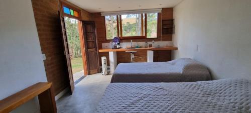 a bedroom with two beds and a desk and windows at Recanto na Mantiqueira - Casa 3Q a 2 km do centro in Gonçalves