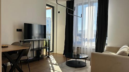 Una sala de estar con un sofá, un televisor y una mesa. en Terra29 apartman, zlatiborski kutak sa besplatnim parkingom, en Zlatibor