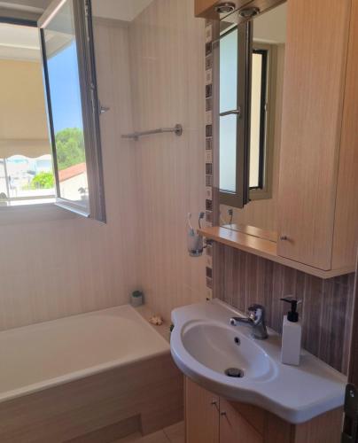 a bathroom with a sink and a mirror and a tub at Onda Blu Deluxe Loutraki in Loutraki