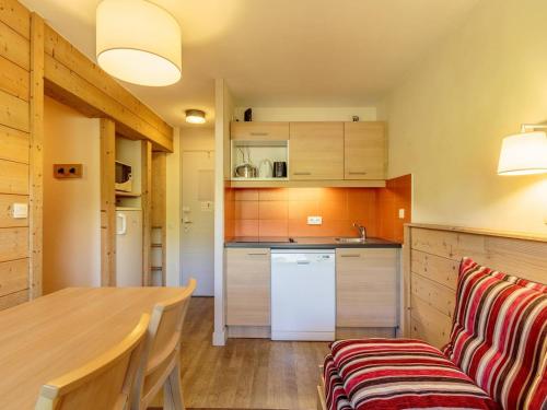 une cuisine avec une table en bois et un canapé dans l'établissement Appartement lumineux avec balcon, Wi-Fi & piscine chauffée à Plagne 1800 - FR-1-351-173, à La Plagne Tarentaise