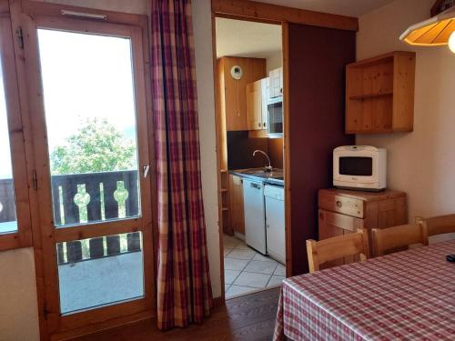 une cuisine avec une table et un four micro-ondes ainsi qu'une fenêtre dans l'établissement Appart 2P au pied des pistes, animaux admis, Valmorel - FR-1-356-190, à Valmorel