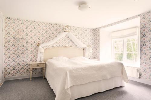 una camera da letto con un letto bianco e carta da parati floreale di Bäckaskog Slott a Fjälkinge