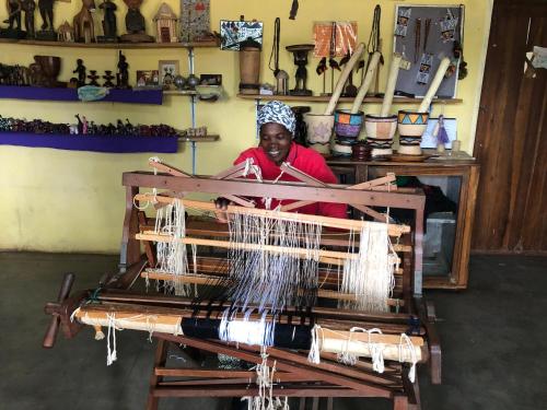 a woman is working on a weaving machine at Tiko Community Centre in Saint Francis