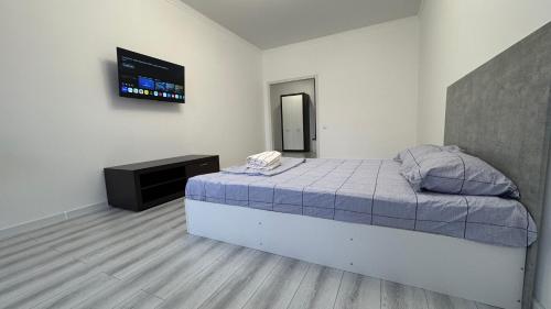 a bedroom with a bed and a tv on the wall at Новая большая 1-ком кв ЖК Satym мкр Батыс-2 in Aktobe