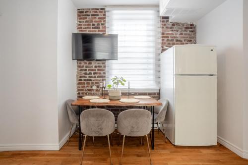 a kitchen with a table with chairs and a refrigerator at Premium Location Stylish 3BR downtown Montreal in Montréal