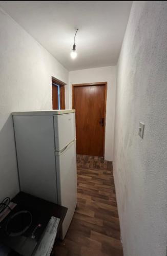 a kitchen with a refrigerator and a wooden door at APARTMENTS Mir in Virpazar